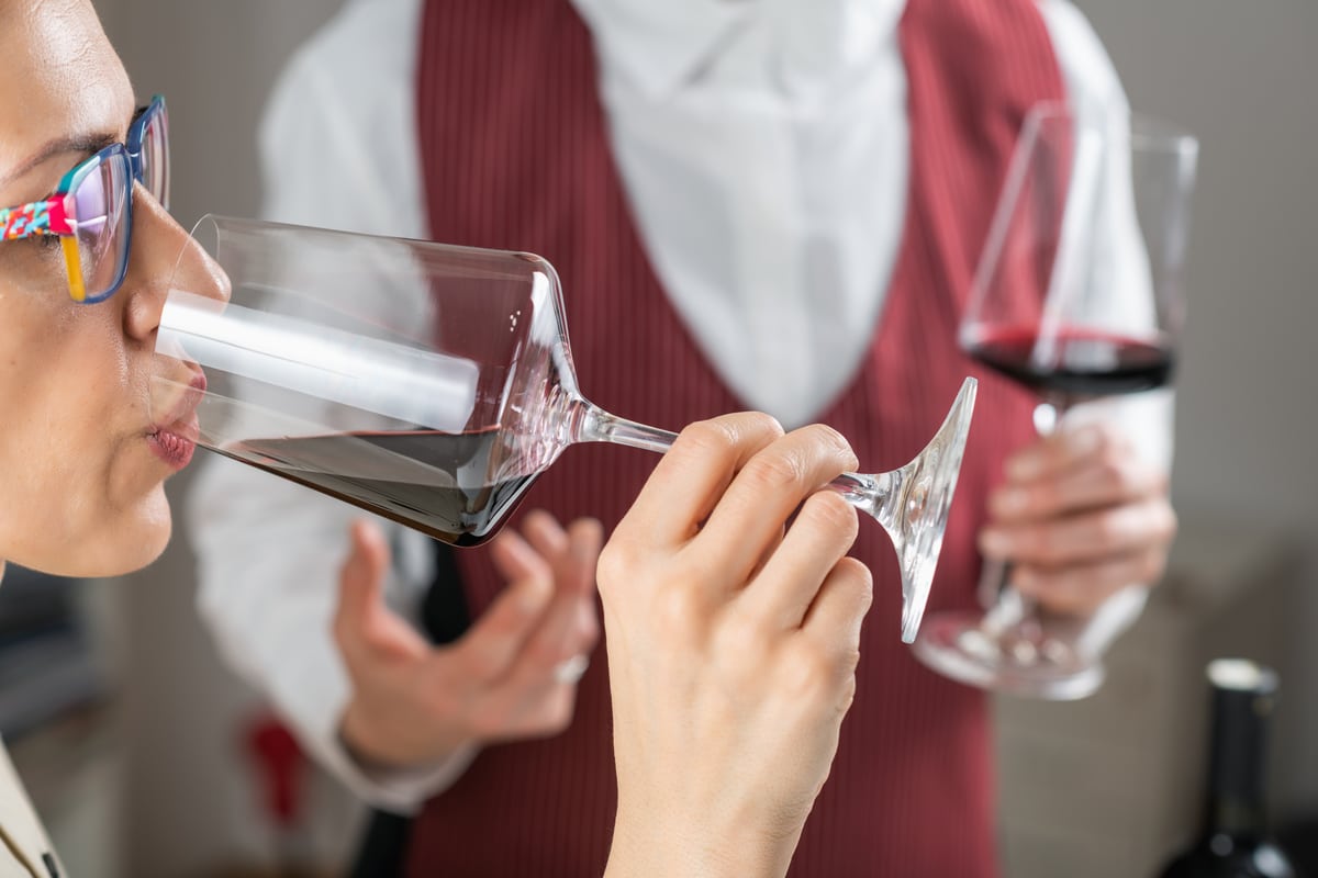 Kobieta degustująca czerwone wino w obecności sommeliera — zdjęcie ilustracyjne