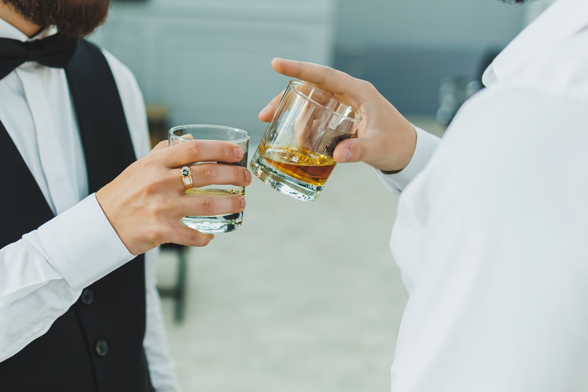 Dwie osoby trzymające szklanki z bursztynowym alkoholem — zdjęcie ilustracyjne